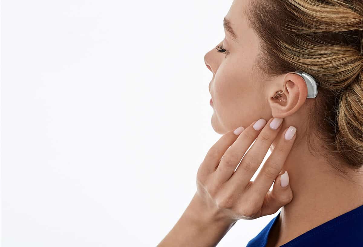 woman holding ear with hearing aid
