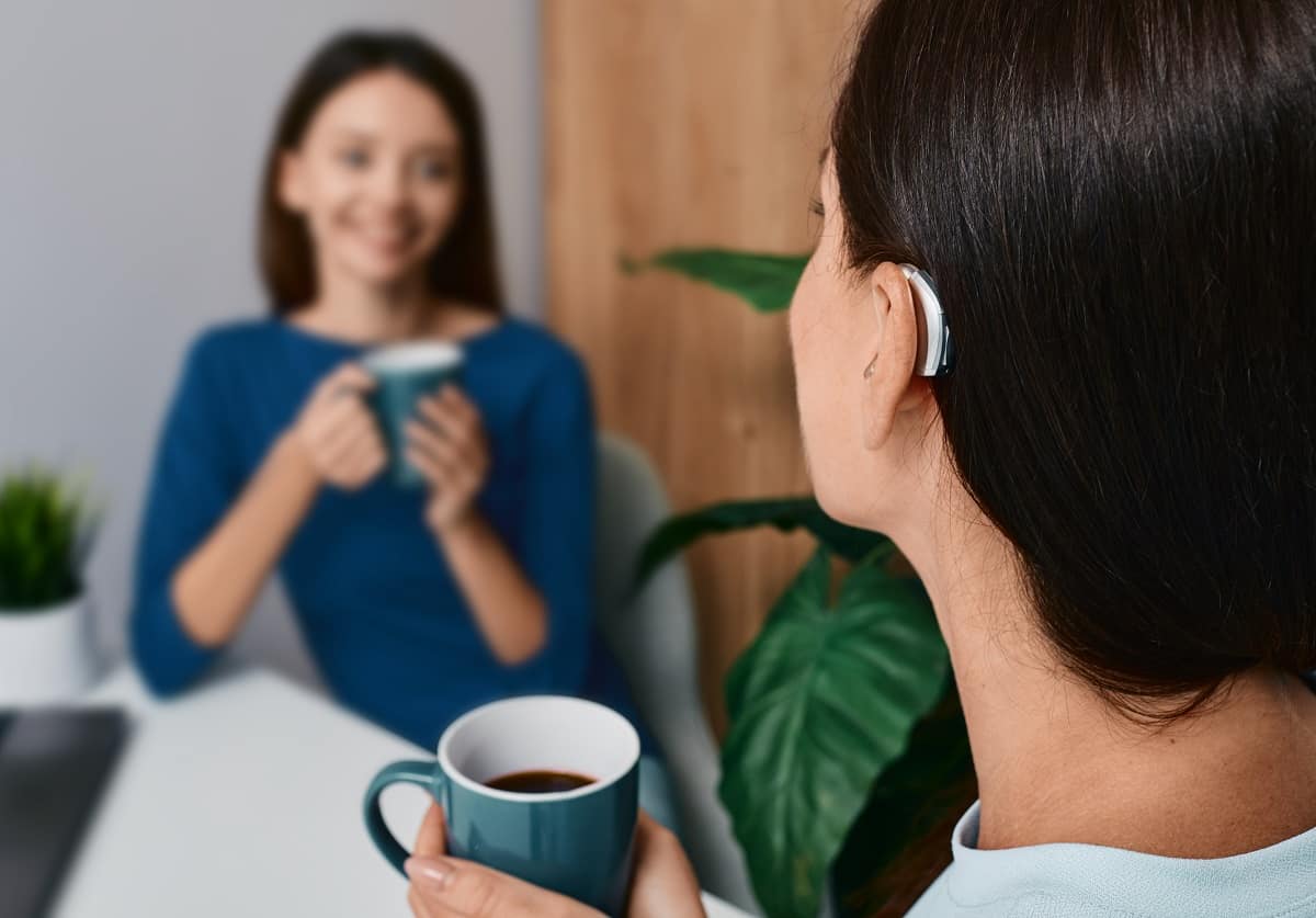 Woman with hearing aid enjoying coffee with friend
