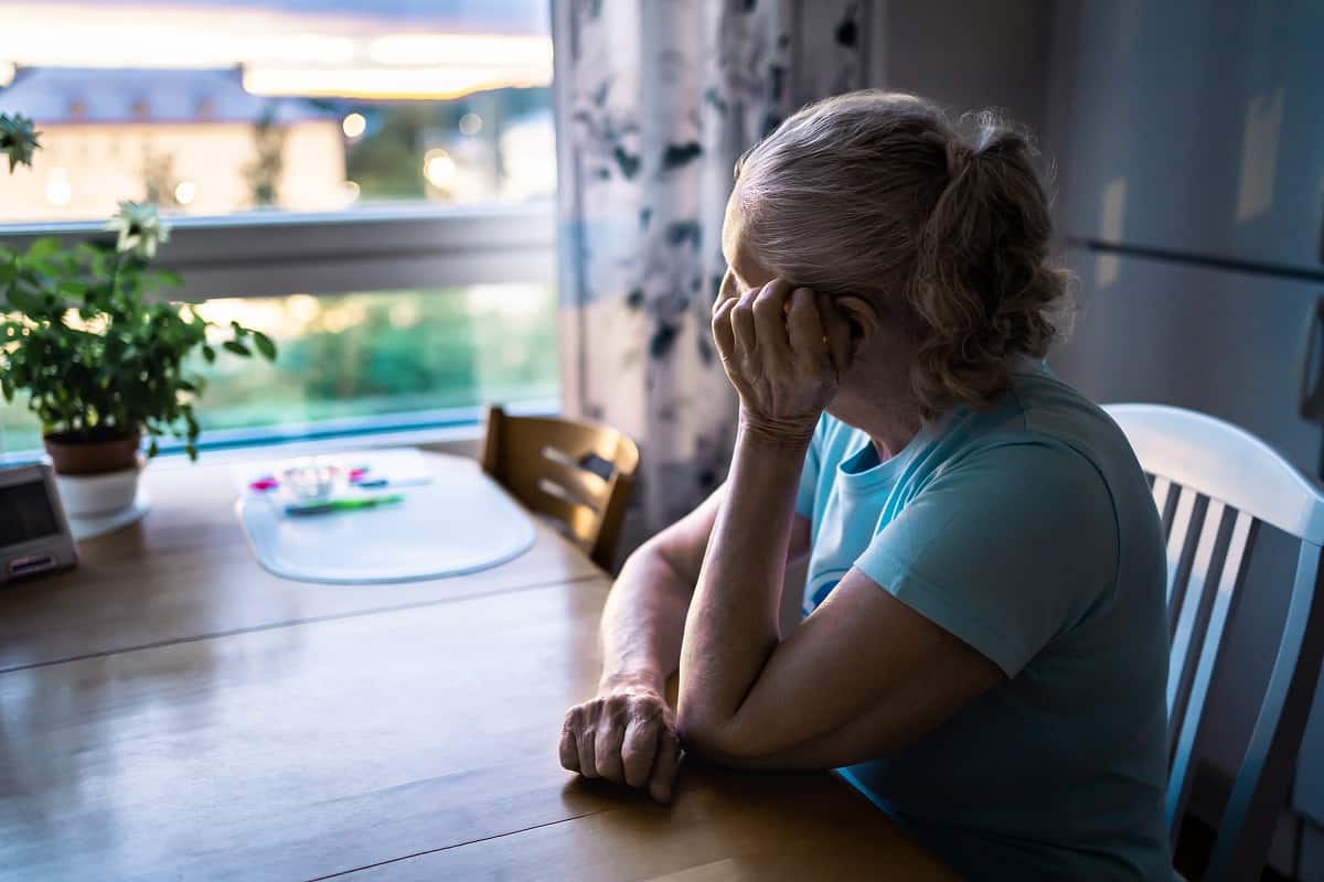 woman looking out window depressed